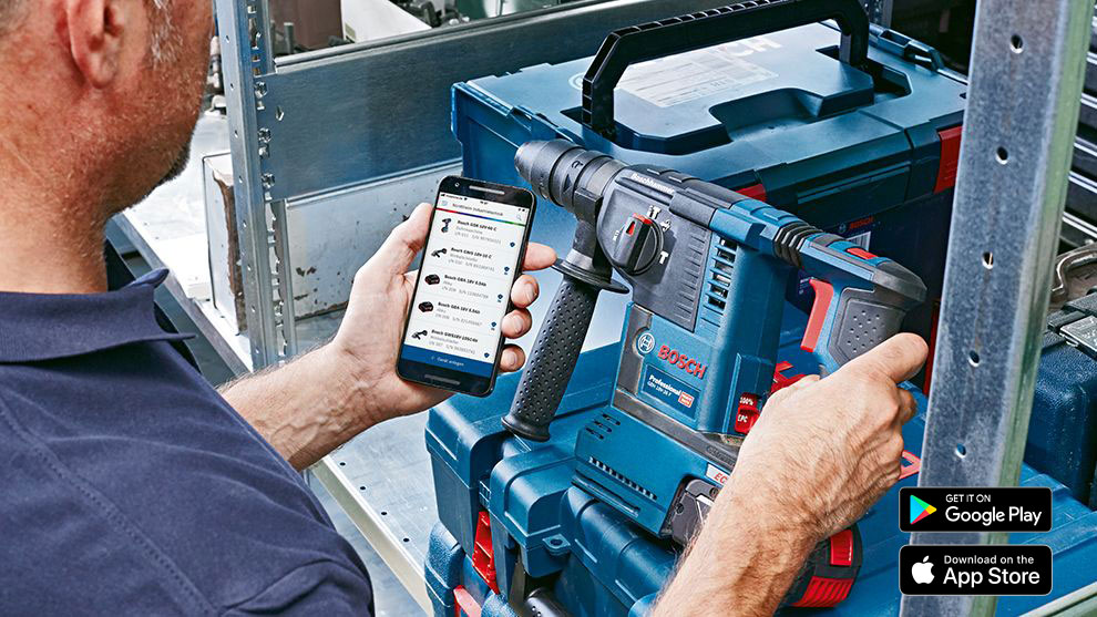 A man holds a smartphone and operates a Bosch Professional drill.
