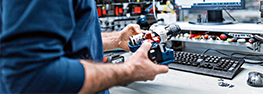 A craftsman holds a blue Bosch Professional tool on a table.