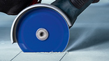 A blue Bosch Professional tile cutter is cutting tiles on a floor.