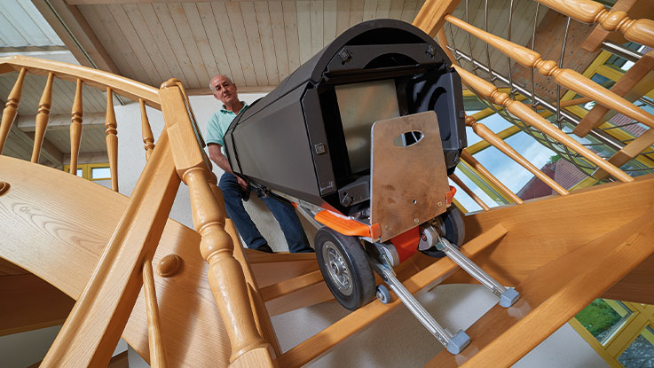 A man is carrying a black toolbox down the stairs.