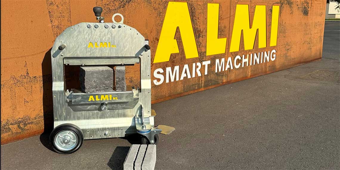 An ALMI machine stands on a gray background in front of a wall.