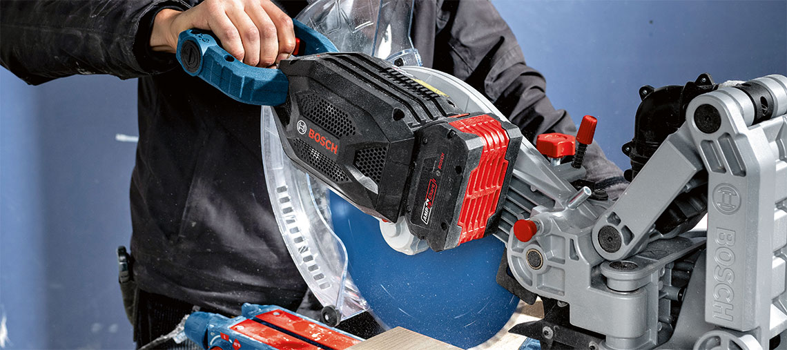 A Bosch Professional miter saw is being operated by a person.
