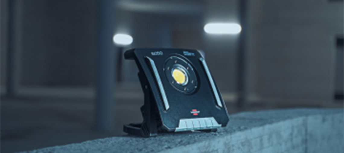 A black Bosch Professional construction light stands on a concrete surface.