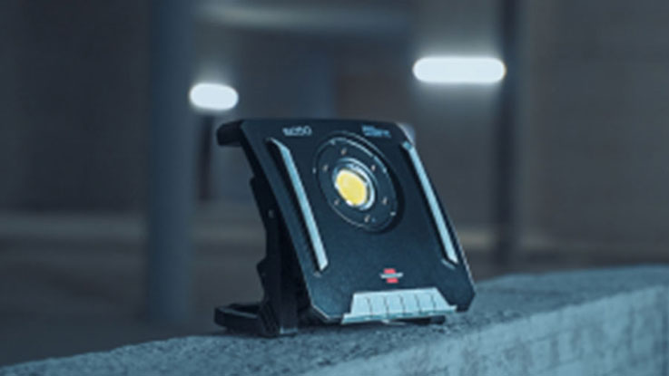 A black Bosch Professional construction light stands on a concrete base.