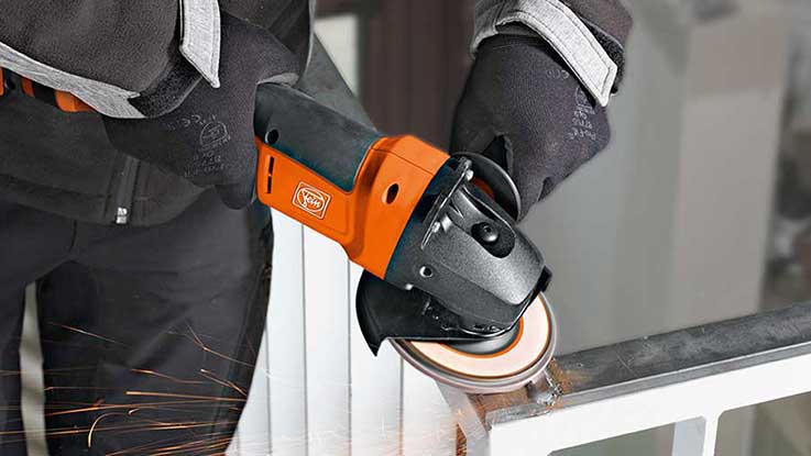 An orange Bosch angle grinder is being used on a piece of metal.