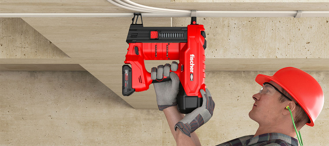 A craftsman with a red helmet is using a red cordless nailer on the ceiling.