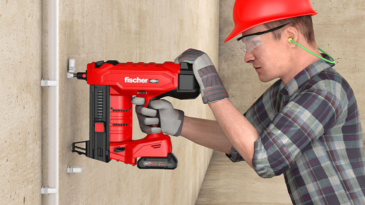 A craftsman with a red fisher battery nailer on a wall.