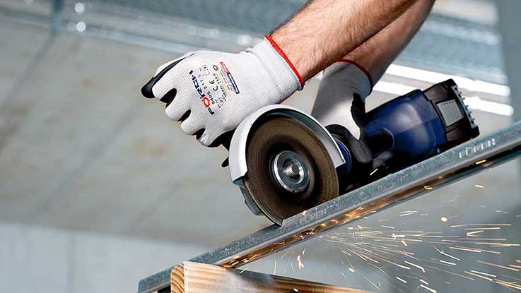 A gloved hand holds a Bosch Professional angle grinder, sparks are flying.