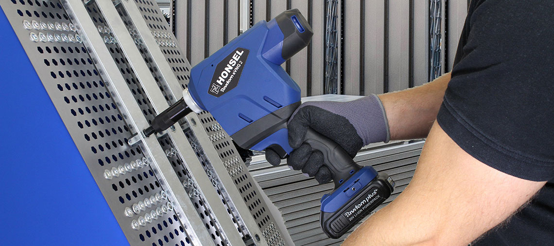 A blue HONSEL battery riveter is used on metal profiles.