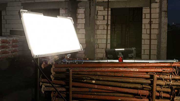 A bright construction light stands on a wooden frame in a room.