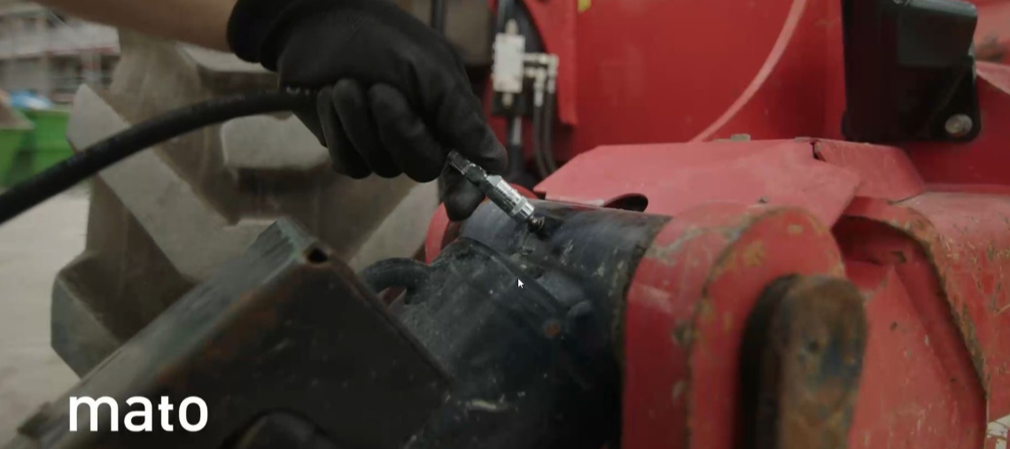 A hand in a black glove operates a red tool.