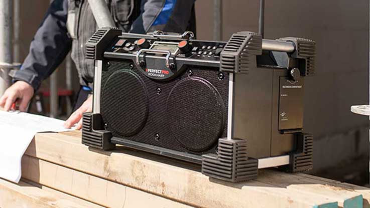 A black Bosch Professional speaker is standing on a stack of wood.