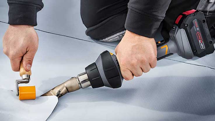 A person is working on a film with a Bosch hot air gun.