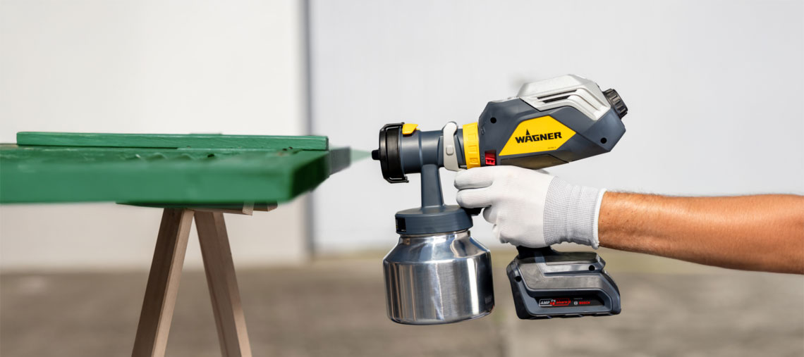 A Wagner paint sprayer is held on a green table.