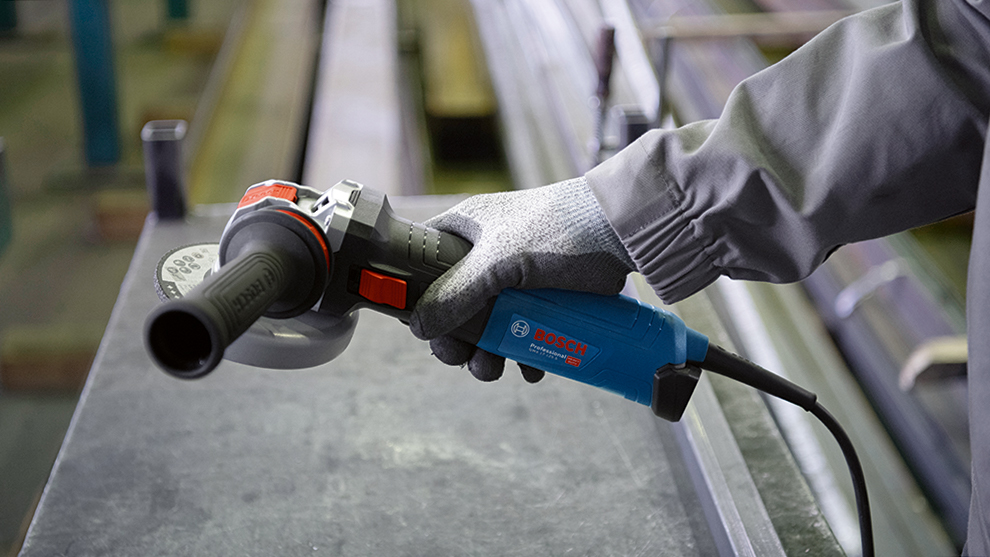 A Bosch Professional angle grinder is held by one hand.