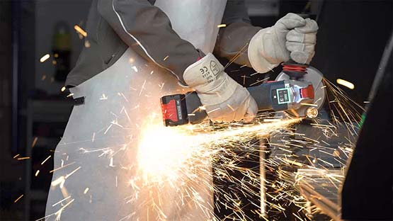 A craftsman wearing protective gloves is using a Bosch angle grinder.