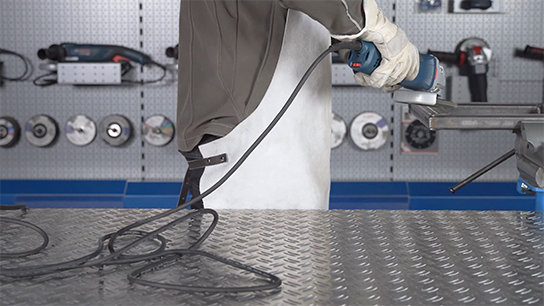 A craftsman is using a Bosch Professional machine on a metal surface.