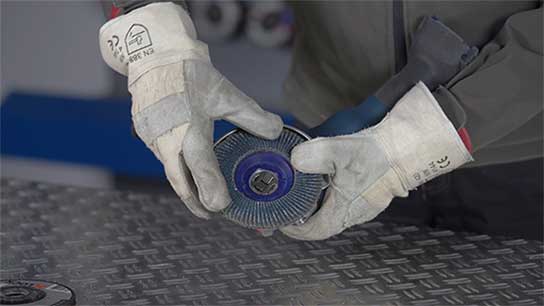 A person in gloves holds a Bosch disc on a table.