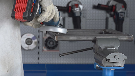 A person holds a Bosch Professional angle grinder over a workpiece.