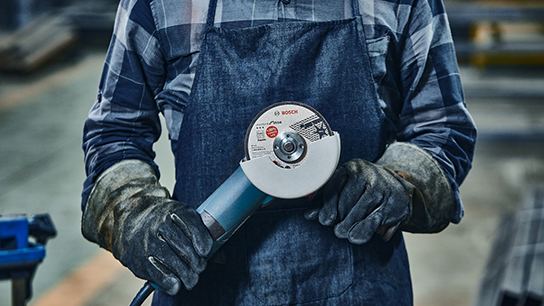A worker is holding a Bosch Professional angle grinder in his hands.