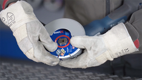 A person in gloves holds a blue Bosch disc.