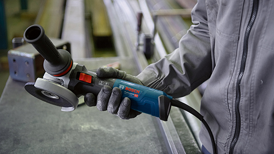 A person is holding a blue Bosch Professional angle grinder in their hand.