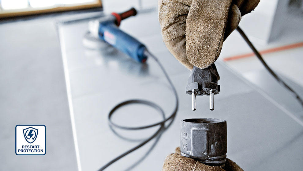 A gloved hand holds a plug over a socket.