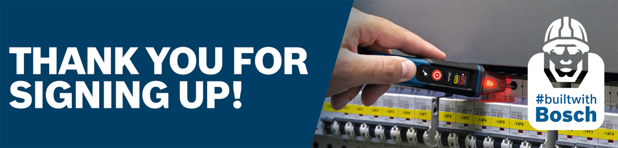 A craftsman holds a testing device to a control cabinet with colored switches.