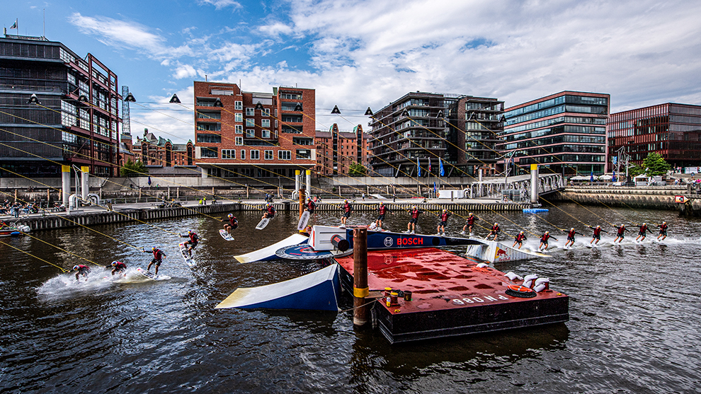 Water sports athletes jump from a red platform in the harbor.