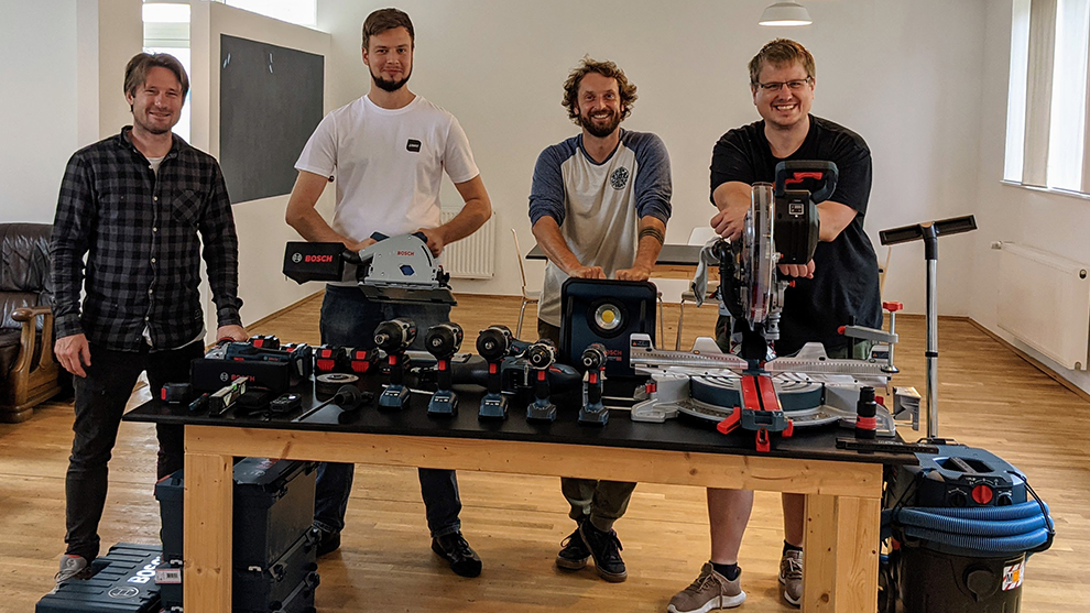 Four men are standing at a table with Bosch tools in a bright room.