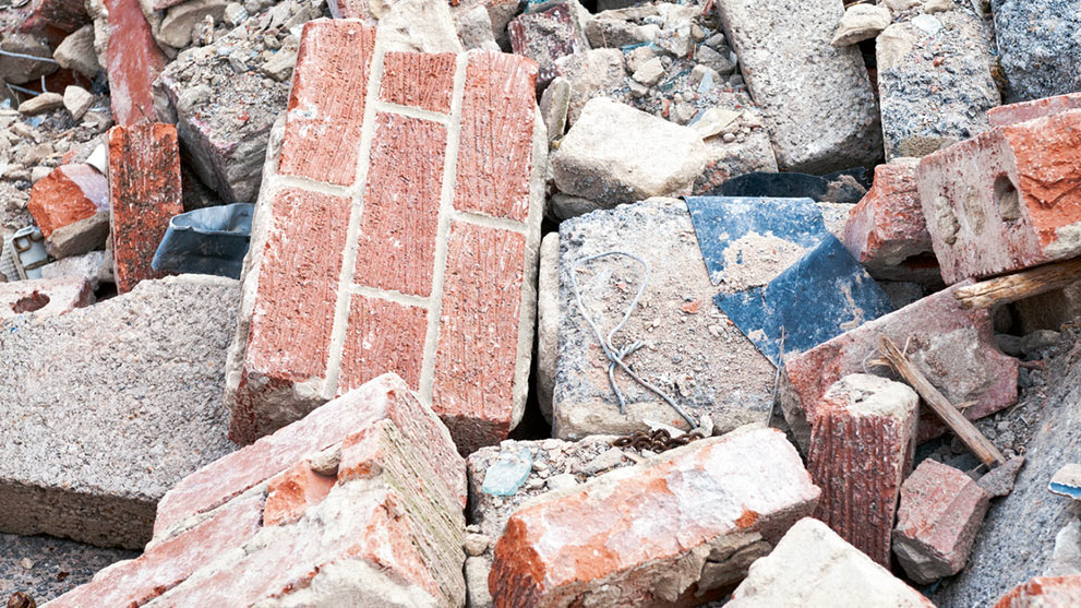 Bricks and concrete blocks are scattered messily on a construction site.