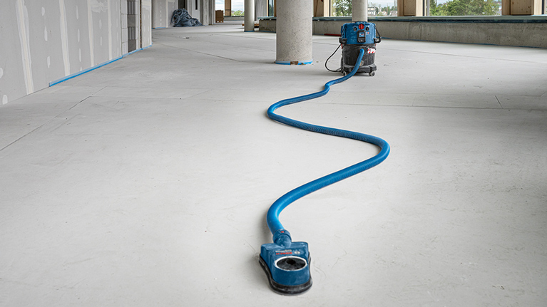 A blue Bosch Professional vacuum cleaner stands on a smooth floor.