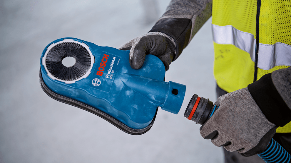 A person is holding a blue Bosch Professional tool with a brush.