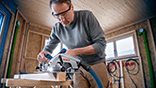 A man is using a Bosch Professional circular saw in a workshop.