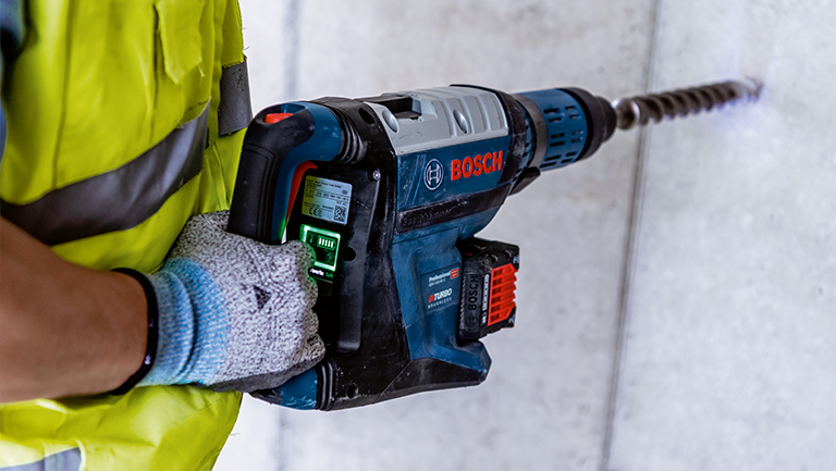 A Bosch Professional cordless hammer drill is held by a person.