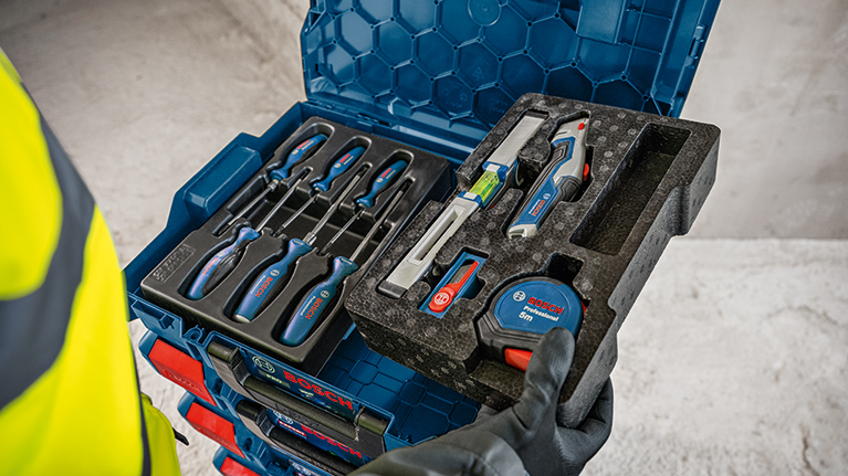 A blue Bosch Professional toolbox is on top of another suitcase, both have red latches. The bottom is gray.