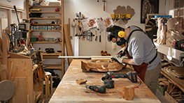 A craftsman is working on a wood project in a workshop.