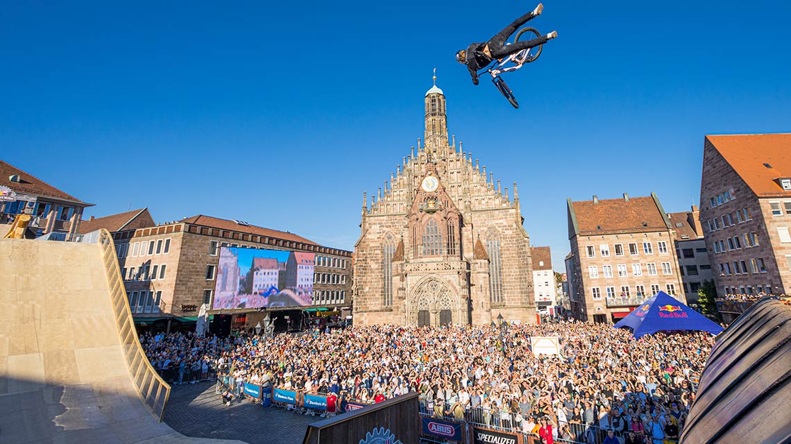 A cyclist jumps over a ramp in front of a large crowd.