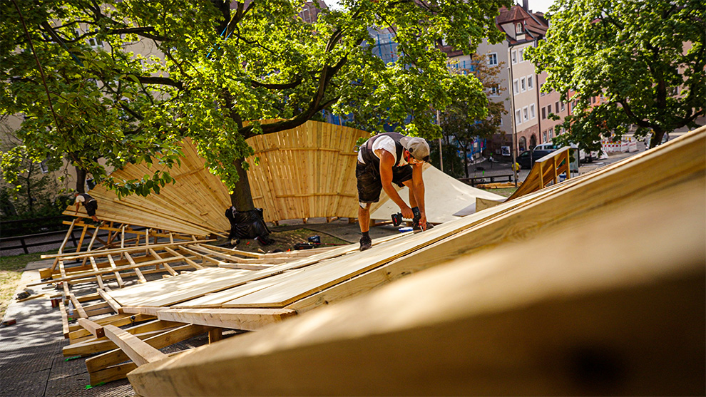 The Wallride was the most challenging slope to build due to the different angles and intersections A craftsman is installing wooden panels on a curved structure.