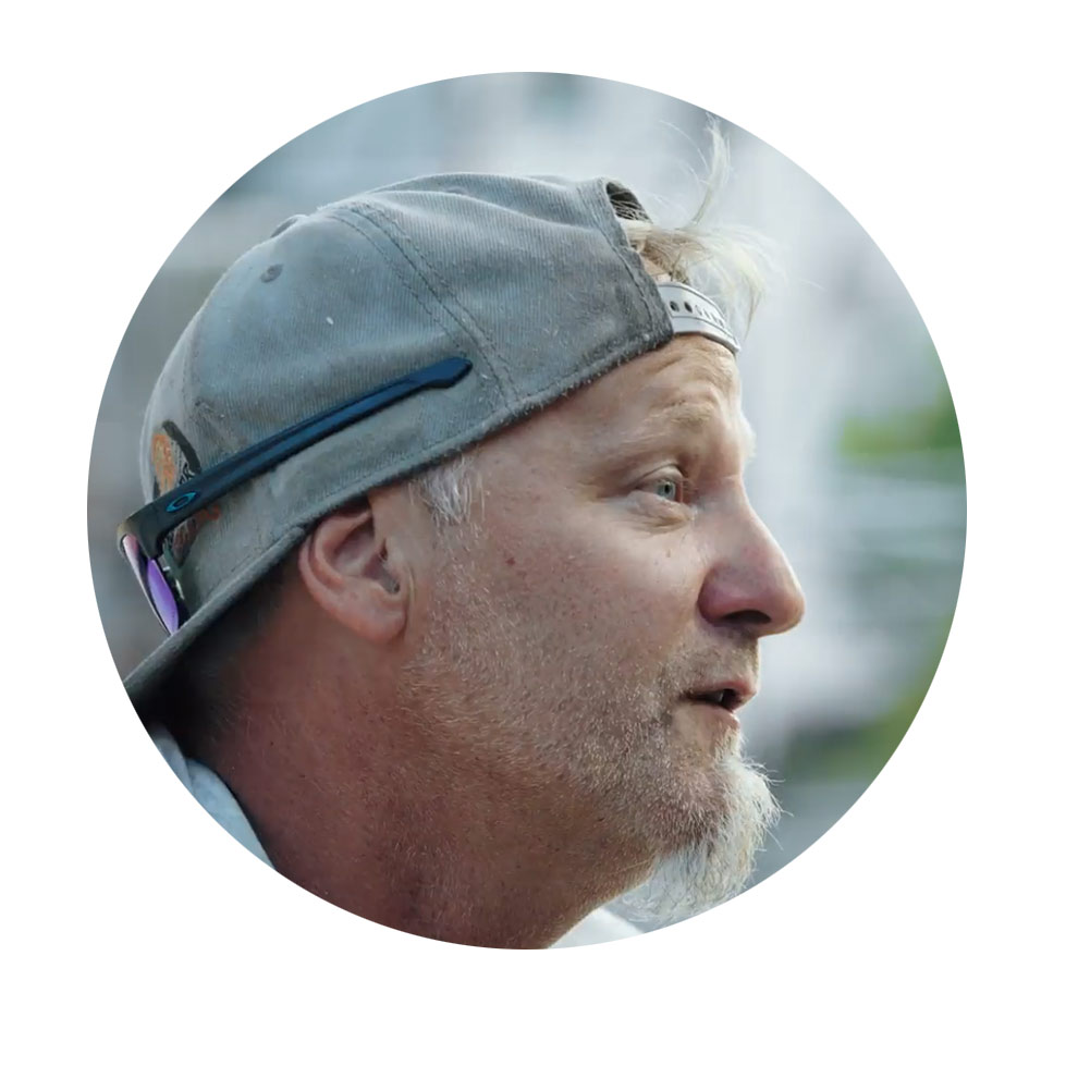 Niko Bößl, Track Designer A man with a gray cap is speaking, his face turned to the side, smiling.