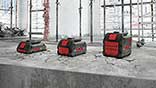 Three Bosch Professional batteries in red and black on a concrete surface.
