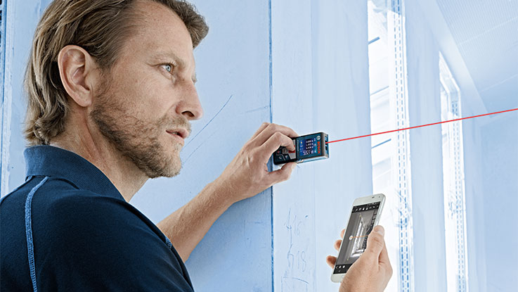 A man is using a Bosch Professional laser device on a wall.