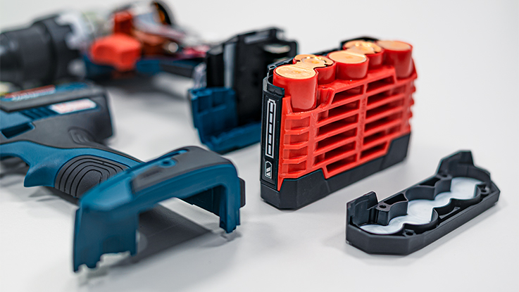Red Bosch Professional battery next to blue tool handle and parts.